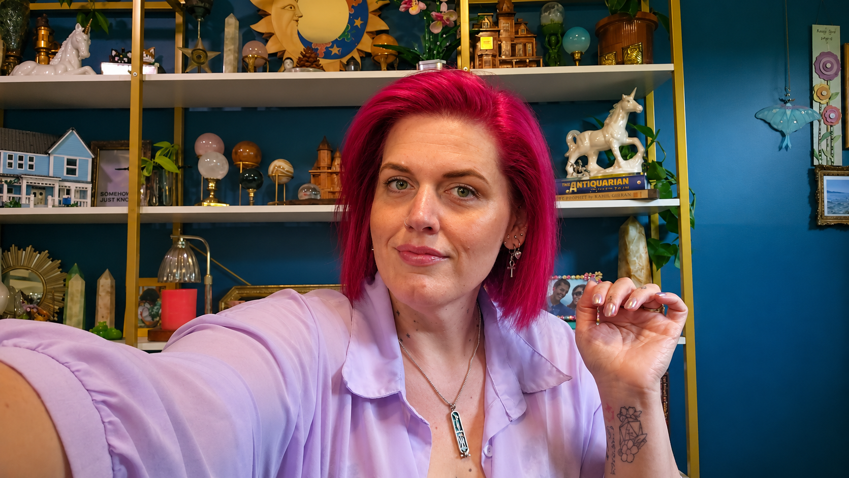 Kayla Winter, founder and author, seated at a table with an open book and apothecary bottles in a lush greenhouse setting
